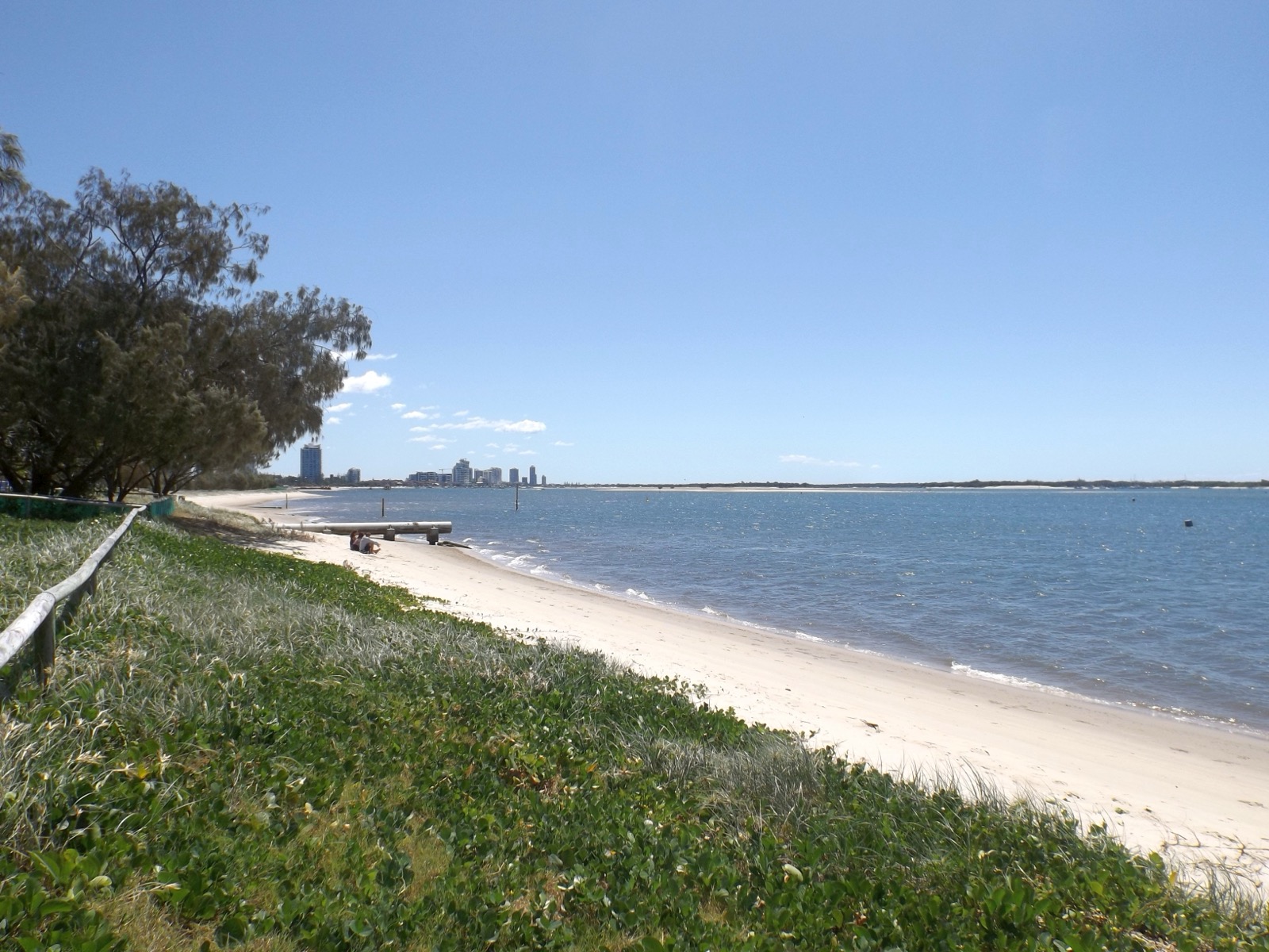 broadwater-parklands-gold-coast-show-2026 Sandy foreshore and grassy dune at Broadwater Parklands, Southport, with the Southport skyline across the Broadwater